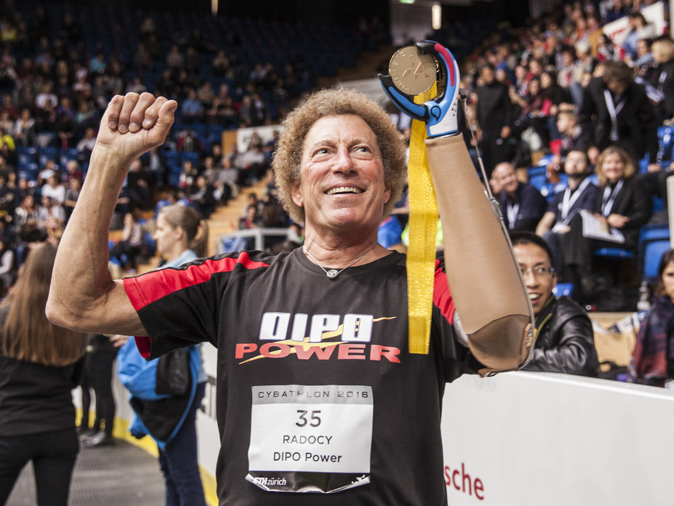 Bob Radocy, winner of the 2016 Cybathlon, holding his medal with his prosthetic.